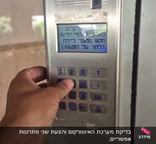 יד לוחצת על מקלדת אינטרקום בבניין